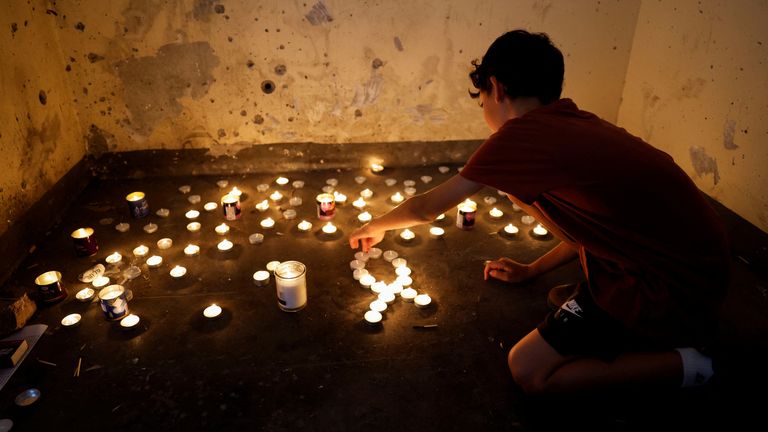 A boy lights memorial candles inside a bomb shelter in which people were killed during the deadly October 7 attack by Hamas from Gaza, on the first anniversary since the attack, near Kibbutz Mefalsim in southern Israel, October 7, 2024. REUTERS/Amir Cohen