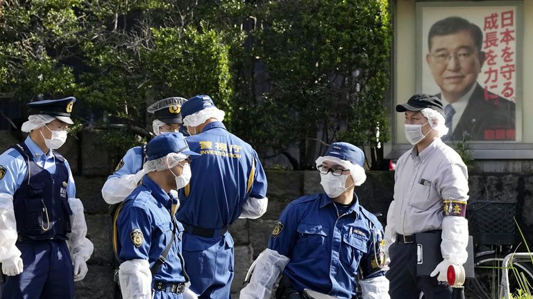 Police officers near the headquarters of Japan's Liberal Democratic Party with a poster of Japan's Prime Minister Shigeru Ishiba. Pic: AP