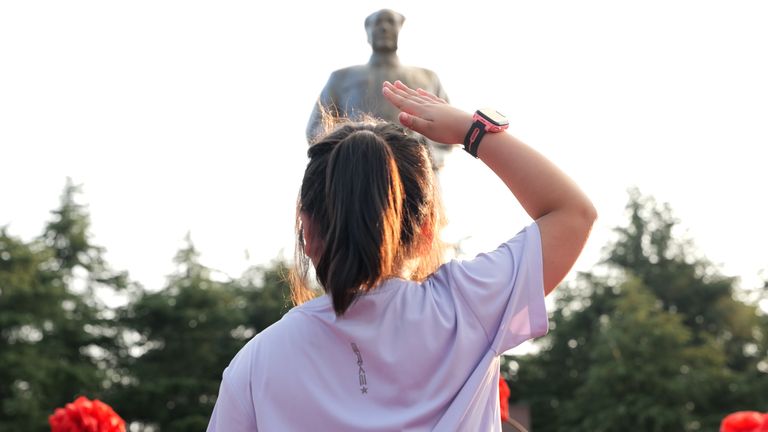 Girl salutes statue of Mao Zedong at the site of his childhood home in Shaoshan village, Hunan province