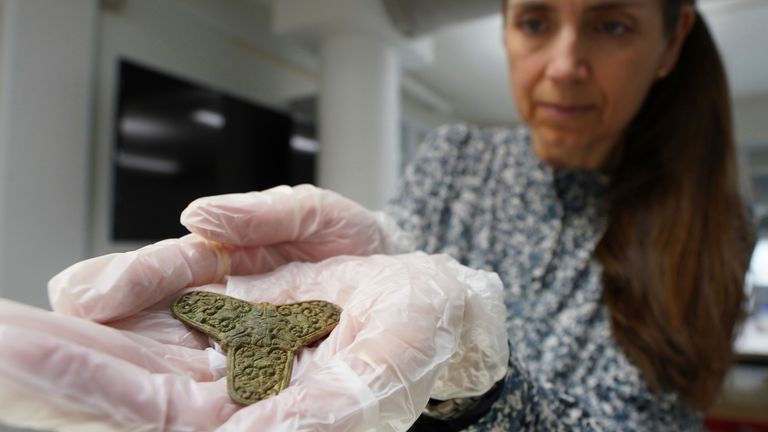 Jannie Amsgaard Ebsen, conservator at Museum Odense, holds a brooch, discovered at the excavation site of a 10th century Viking burial ground in Aasum, Denmark, Monday, Oct. 7, 2024. (AP Photo/James Brooks)