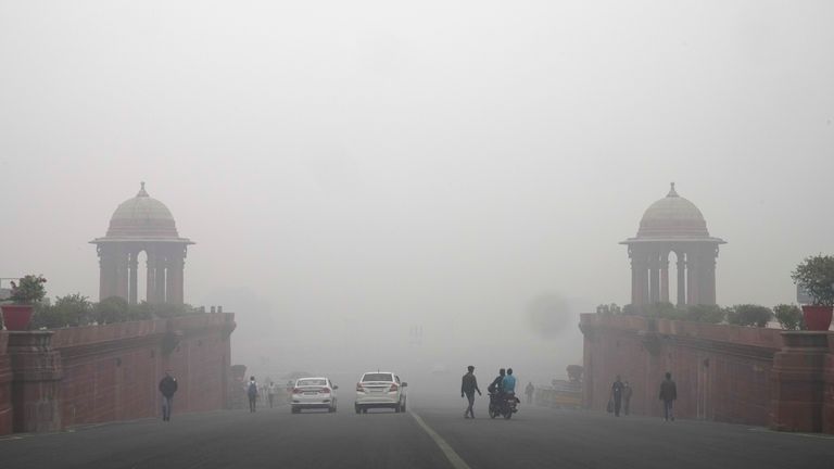 Office goers walk wearing a face mask amidst a thick layer of smog as air pollution shoots up in New Delhi, India, Monday, Nov. 18, 2024. (AP Photo/Manish Swarup)