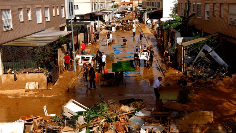 People clean up a mud-covered street after heavy rains in Alfafar.
Pic: Reuters