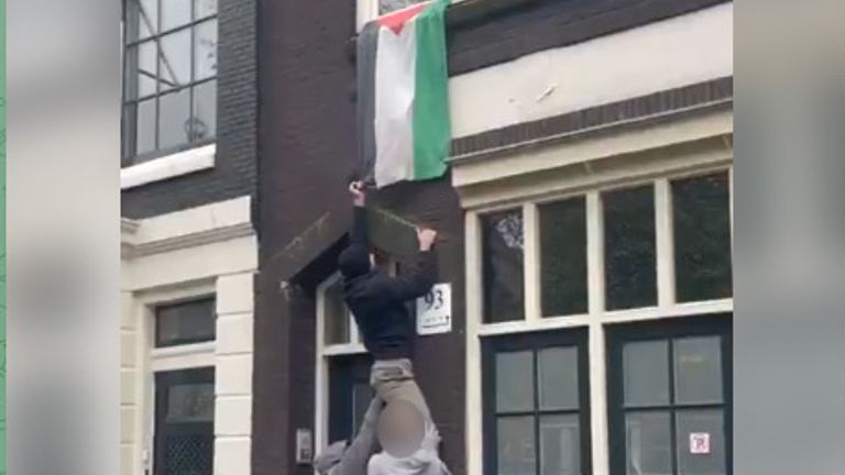 Three men pull down a Palestinian flag in the city centre