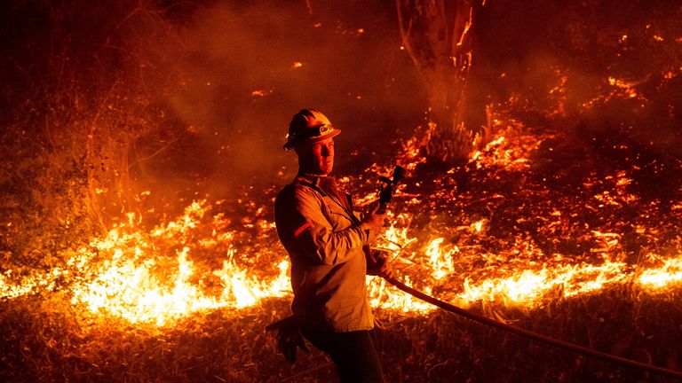 A firefighter prepares to douse flames while battling the Mountain Fire on Wednesday, Nov. 6, 2024, in Santa Paula, Calif. (AP Photo/Noah Berger)