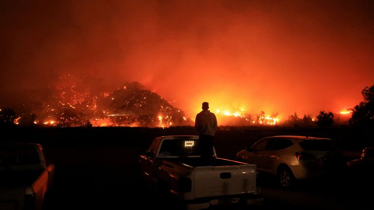 A person looks on as smoke and flames billow from the Mountain Fire in Santa Paula, California, U.S., November 6, 2024. REUTERS/David Swanson TPX IMAGES OF THE DAY