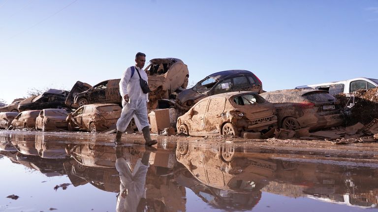 A man walks past stacked up cars after floods in Catarroja.
Pic: AP