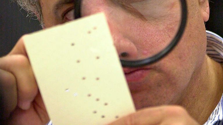 FILE - In this Nov. 24, 2000 file photo, Broward County, Florida Board member Judge Robert Rosenberg examines a disputed ballot with a magnifying glass at the Broward County Courthouse in Fort Lauderdale, Florida. What happens when America wakes up? On November 9th, a contentious presidential election in which the outcome hinges on razor-thin results in one or two states, one candidate seeks a recount and the other goes to court? (AP Photo/Alan Diaz, File)