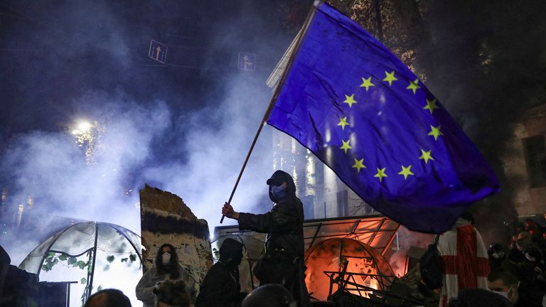 A protester brandishes an EU flag as demonstrations continue in Tbilisi on Saturday. Pic: Reuters