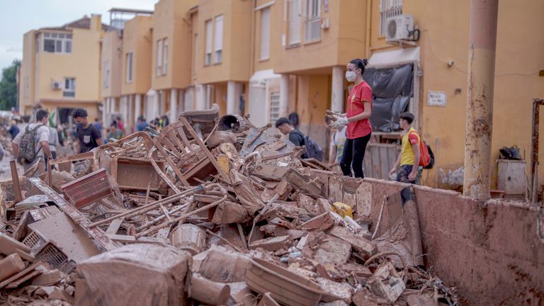 A woman stacks belongings covered in mud from a house in Catarroja, Spain.
Pic AP