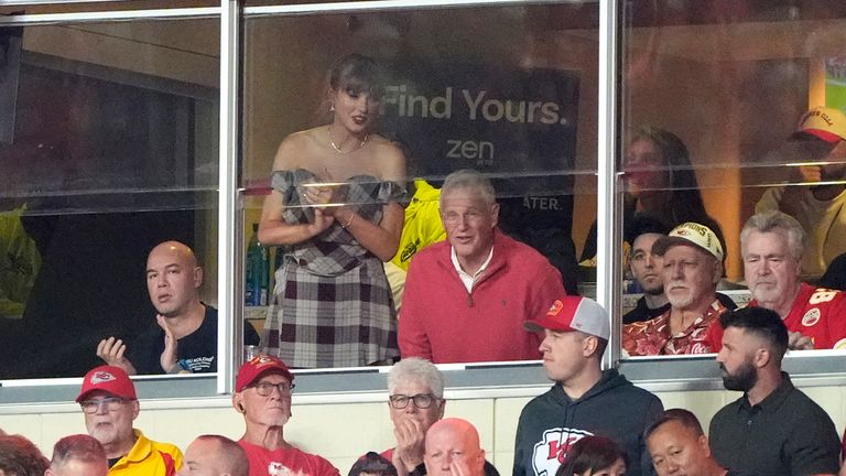 Taylor Swift stoi i obserwuje z apartamentu obok swojego taty Scotta Swifta pierwszą połowę meczu piłkarskiego NFL pomiędzy Kansas City Chiefs a New Orleans Saints, poniedziałek, 7 października 2024 r., w Kansas City w stanie Missouri (AP Zdjęcie/Charlie Riedel)