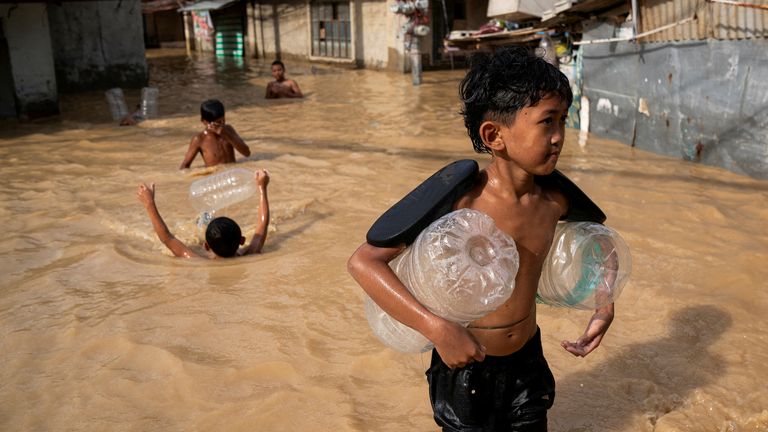 Children play along a flooded street following super typhoon Man-Yi, in Cabanatuan, Nueva Ecija, Philippines, November 18, 2024. REUTERS/Lisa Marie David TPX IMAGES OF THE DAY