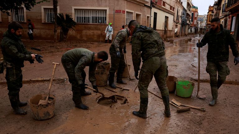 Army personnel clean a drainage system blocked by mud in Paiporta, Valencia. Pic: Reuters