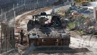 An Israeli soldier stands next to a military vehicle, as soldiers gather near the ceasefire line between Syria and the Israeli-occupied Golan Heights