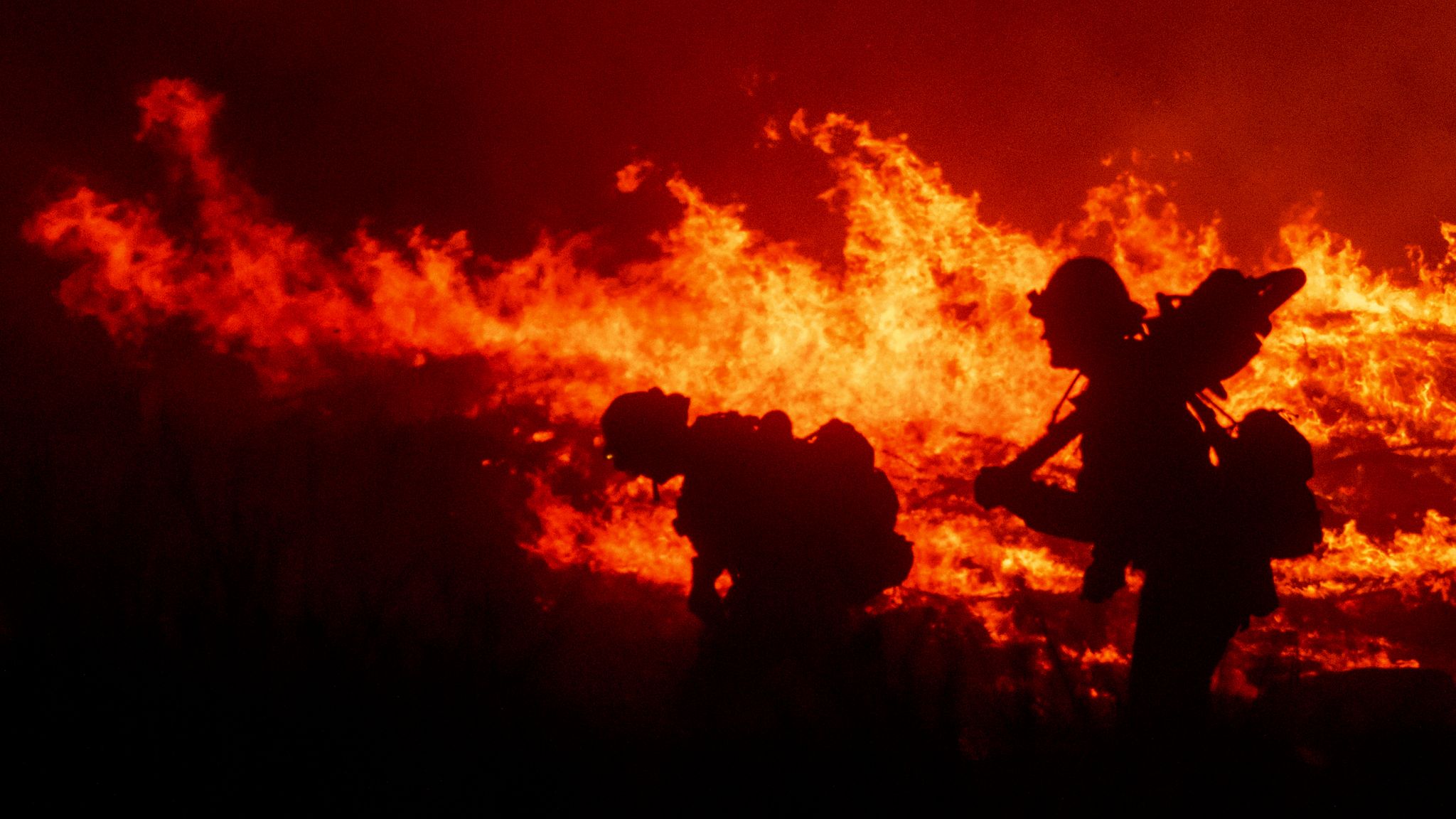 Archival file photo: firefighters during an earlier Southern California wildfire Firefighters silhouetted against flames during an earlier Southern California wildfire response