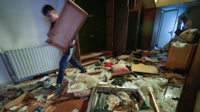 A man walks by a broken portrait of the late Syrian President Hafez Assad as people search for belongings in the ransacked private residence of Syrian President Bashar Assad in Damascus, Syria, on Sunday, Dec. 8, 2024. (AP Photo/Hussein Malla)