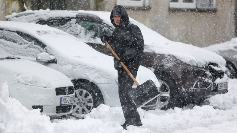 A man shovels snow from the street during heavy snowfall in Bihac, Bosnia, Monday, Dec. 23, 2024. (AP Photo/Edvin Zulic)