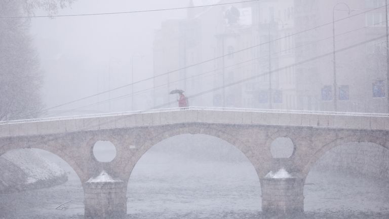 A man walks over a bridge during heavy snowfall in downtown Sarajevo, Bosnia, Monday, Dec. 23, 2024. (AP Photo/Armin Durgut)