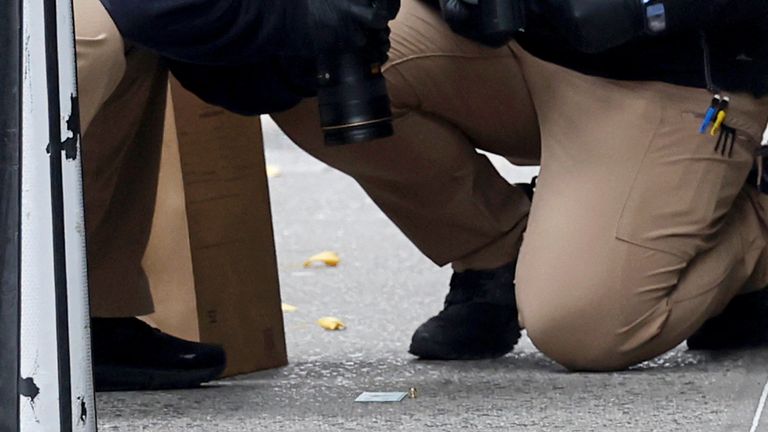 A member of the NYPD Crime Scene Unit takes a picture of a shell casing found at the scene where the CEO of UnitedHealthcare Brian Thompson was  shot and killed in Midtown Manhattan