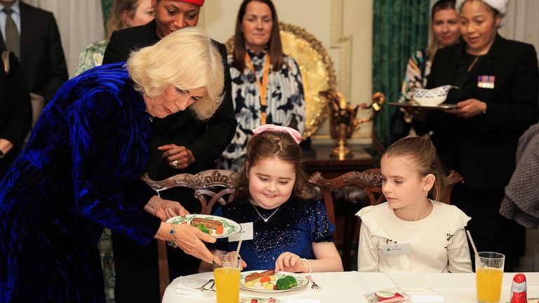 Królowa Camilla trzyma talerz z jedzeniem, gdy spotyka się z rodzicami i dziećmi wspieranymi przez Helen & Douglas House i organizację charytatywną Marvelous Children's Charity Roalda Dahla w Clarence House w Londynie. Data zdjęcia: czwartek, 12 grudnia 2024 r. Mina Kim/PA Wire