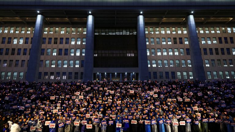 Bidh daoine a’ cumail choinnlean agus shoidhnichean aig àm faire coinneal gus iarraidh air Ceann-suidhe Corea a Deas Yoon Suk Yeol a dhreuchd a leigeil dheth.  Dealbh: Reuters