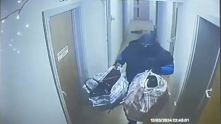 One of the two robbers carrying two large bags containing branded goods.