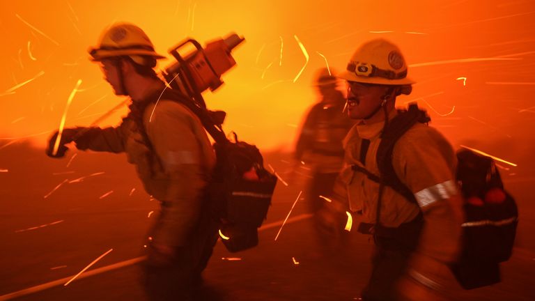 Firefighters are pushed back by gusty winds while removing fuel around the faculty and staff residences at Pepperdine University as the Franklin Fire approaches in Malibu, Calif., Tuesday, Dec. 10, 2024. (AP Photo/Jae C. Hong)