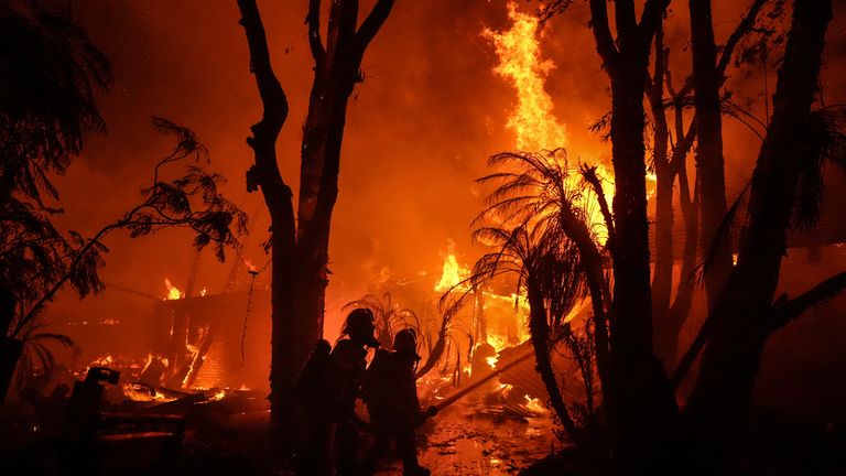 Firefighters spray water on a home as it burns in the Franklin Fire in Malibu, Calif., Tuesday, Dec. 10, 2024. (AP Photo/Jae C. Hong)