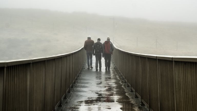 People walk over a foot bridge in foggy conditions near Saddleworth Moor on Saturday. Pic: PA