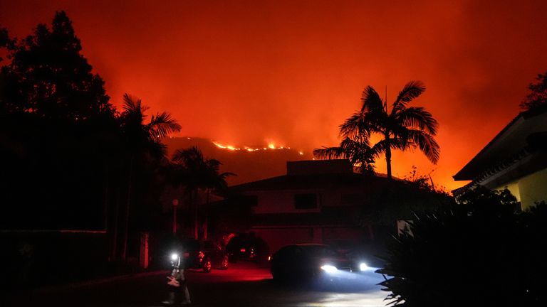 A person evacuates a residence at Pepperdine University as the Franklin Fire approaches in Malibu, Calif., Tuesday, Dec. 10, 2024. (AP Photo/Jae C. Hong)