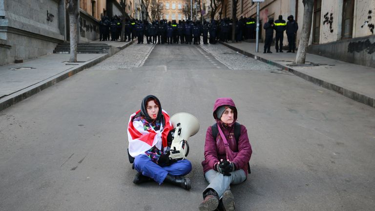 Georgian protesters sit in the street in front of police.
Pic: AP