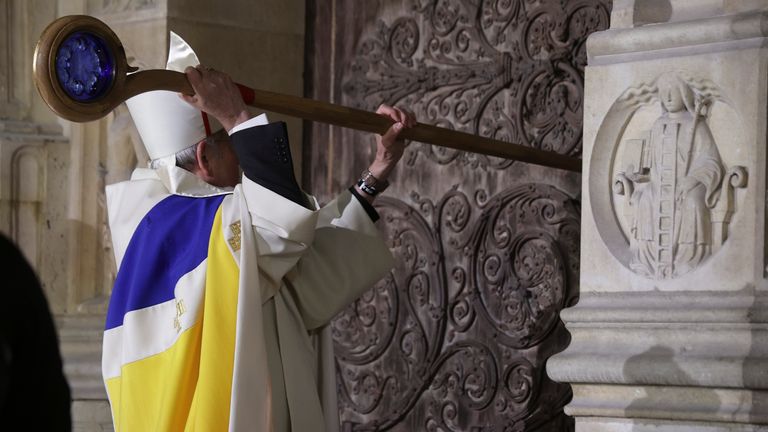 Paris' archbishop Laurent Ulrich knocks on the doors of Notre-Dame Cathedral during its formal reopening. Pic: AP