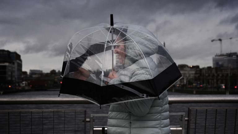 A person takes shelter under an umbrella as they cross the Sean O'Casey Bridge in Dublin's city centre. Storm Darragh is approaching the UK and Ireland and is expected to bring winds of up to 80mph and heavy rain on Friday and into the weekend. Picture date: Friday December 6, 2024.

