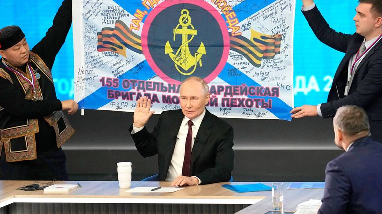 Men hold the banner of the 155th Marine Brigade of the Pacific Fleet participating in the war in Ukraine during Vladimir Putin's annual news conference. Pic: AP