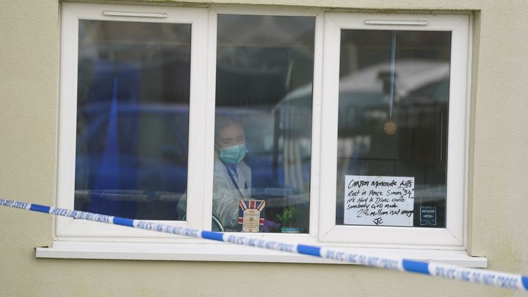 A forensic investigator is seen at a property in Redditch with a tribute in the window. Photo: PA