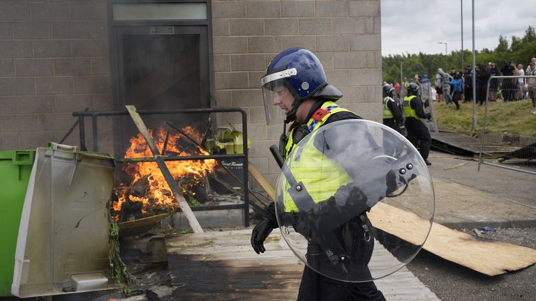 A police officer walks past a fire as trouble flares during an anti-immigration protest outside the Holiday Inn Express in Rotherham, South Yorkshire. Picture date: Sunday August 4, 2024. PA 