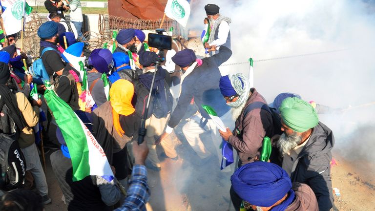 Farmers run for cover after police fired tear gas to disperse protesting farmers who were marching to New Delhi near the Punjab-Haryana border at Shambhu, India, Friday, Dec. 6, 2024. (AP Photo/Rajesh Sachar)