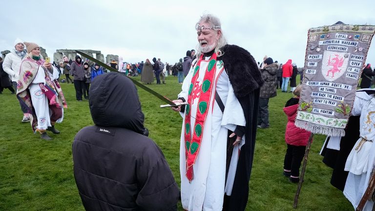 Arthur Pendragon 'knights' a member of the public as they take part in the winter solstice celebrations during sunrise at the Stonehenge prehistoric monument on Salisbury Plain in Wiltshire. Picture date: Saturday December 21, 2024.