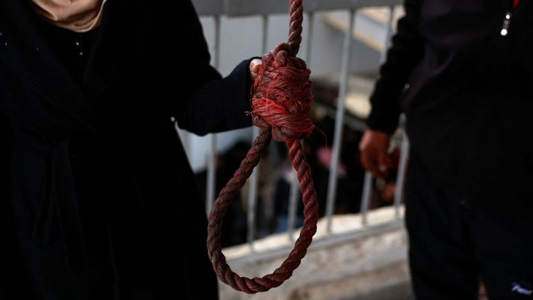 One of the people who went to the prison in search of relatives holds a noose.
Pic: Reuters