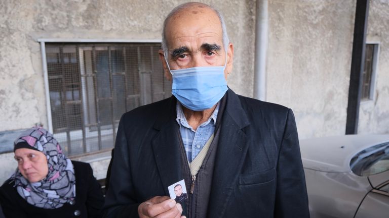 A man holds up a picture of a missing relative in Damascus, Syria. 