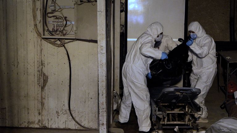 Workers bring through a body into the examination room