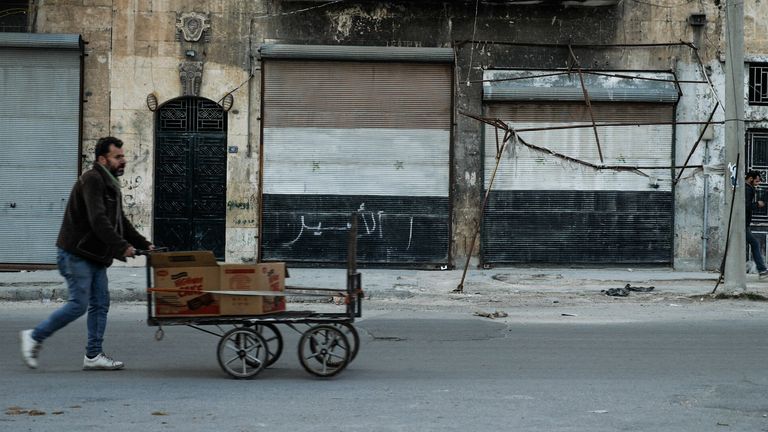 A man pushes his goods along an empty street in eastern Aleppo