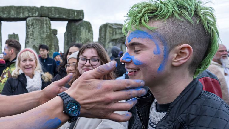 A person's face is daubed with blue paint as they take part in the winter Solstice celebrations at Stonehenge, England, Saturday, Dec. 21, 2024. (AP Photo/Anthony Upton)