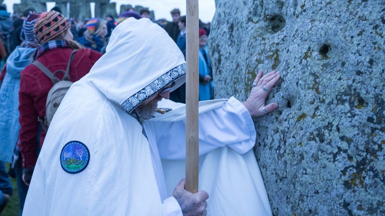 A man lays hands on one of the stones during the winter Solstice celebrations at Stonehenge, England, Saturday, Dec. 21, 2024. (AP Photo/Anthony Upton)