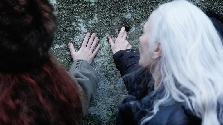 People touch one of the stones as they take part in the winter solstice celebrations during sunrise at the Stonehenge prehistoric monument on Salisbury Plain in Wiltshire. Picture date: Saturday December 21, 2024.