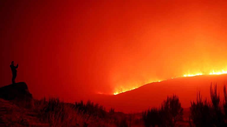 A man stands in the vicinity of wildfire, near Povoa de Montemuro, Portugal, September 18, 2024. REUTERS/Susana Vera          SEARCH "REUTERS BEST 2024" FOR THIS STORY. SEARCH "REUTERS YEAR-END" FOR ALL 2024 YEAR END GALLERIES.          TPX IMAGES OF THE DAY