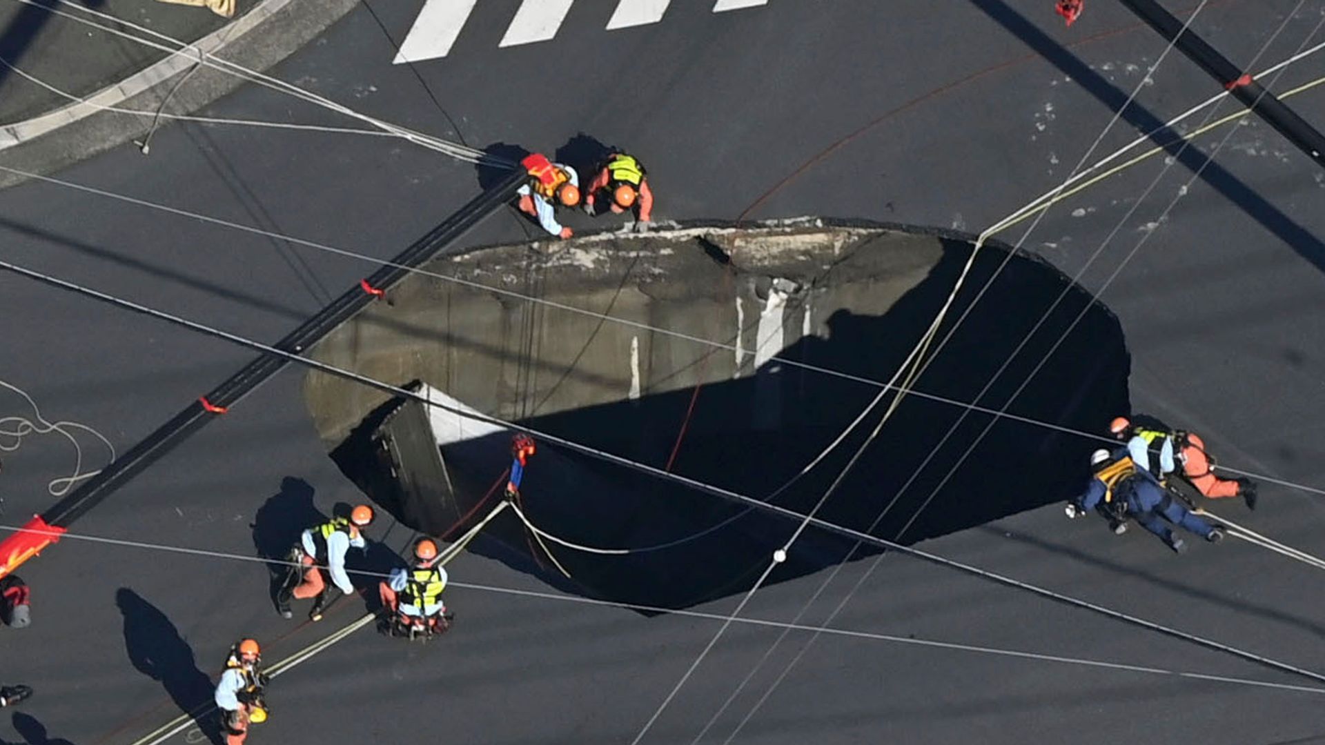 Swimming pool-sized sinkhole swallows truck on busy road, trapping driver