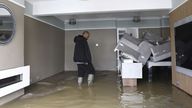 Loughborough resident Qasim Abdullah walks through almost knee-deep water in his living room. Pic AP