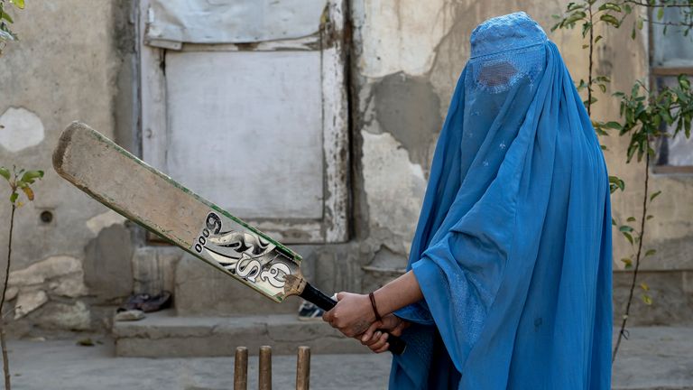 An Afghan woman poses for a photo with her cricket bat in Kabul, Afghanistan, Friday, Nov. 11, 2022. The ruling Taliban have banned women from sports as well as barring them from most schooling and many realms of work. A number of women posed for an AP photographer for portraits with the equipment of the sports they loved. Though they do not necessarily wear the burqa in regular life, they chose to hide their identities with their burqas because they fear Taliban reprisals and because some of them continue to practice their sports in secret. (AP Photo/Ebrahim Noroozi)