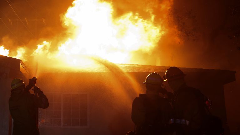Firefighters works to extinguish flames as the Eaton Fire burns in Pasadena, California.
Pic: Reuters