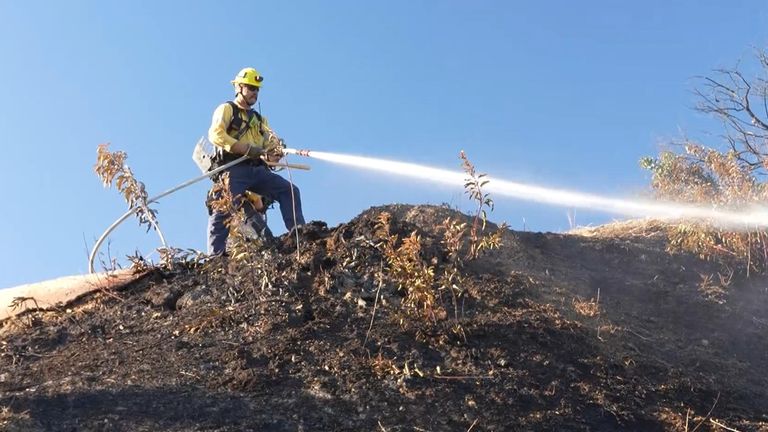 Fire crews are damping down already burnt ground at West Ridge Trailhead